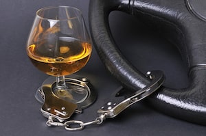 Sniffer glass of whisky handcuffed to a driving wheel